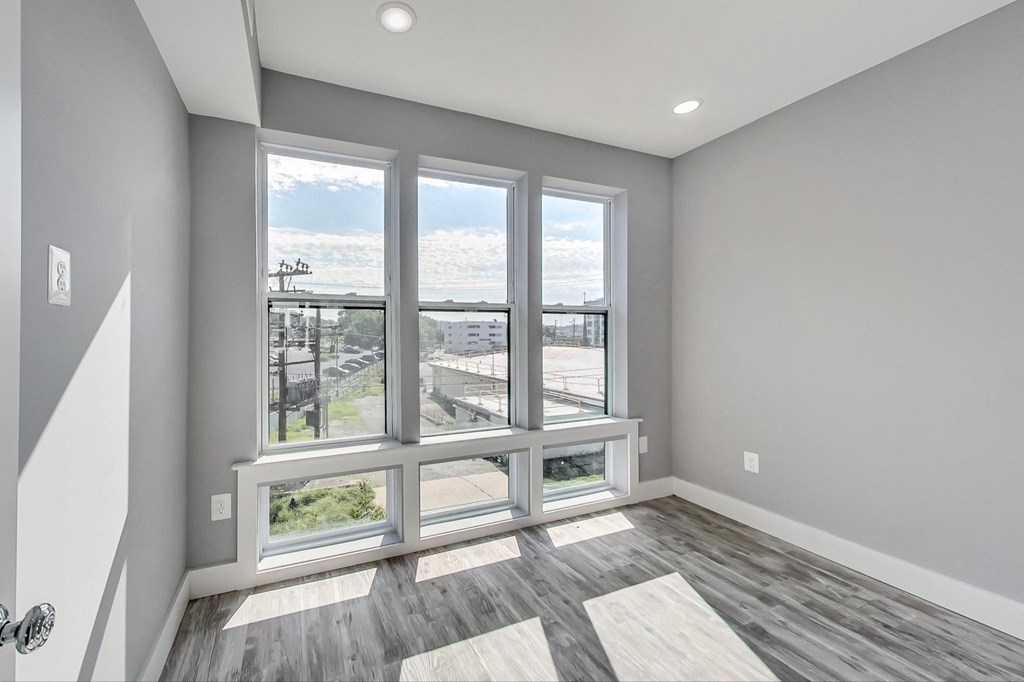 an empty living room with large windows and a view of the city