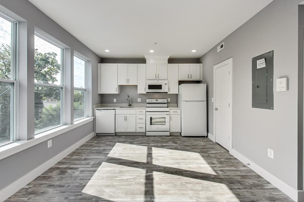 an empty kitchen with white appliances and a large window