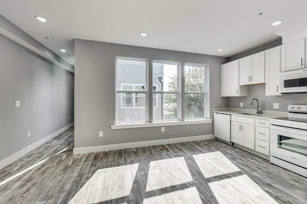 an empty kitchen with white cabinets and a large window
