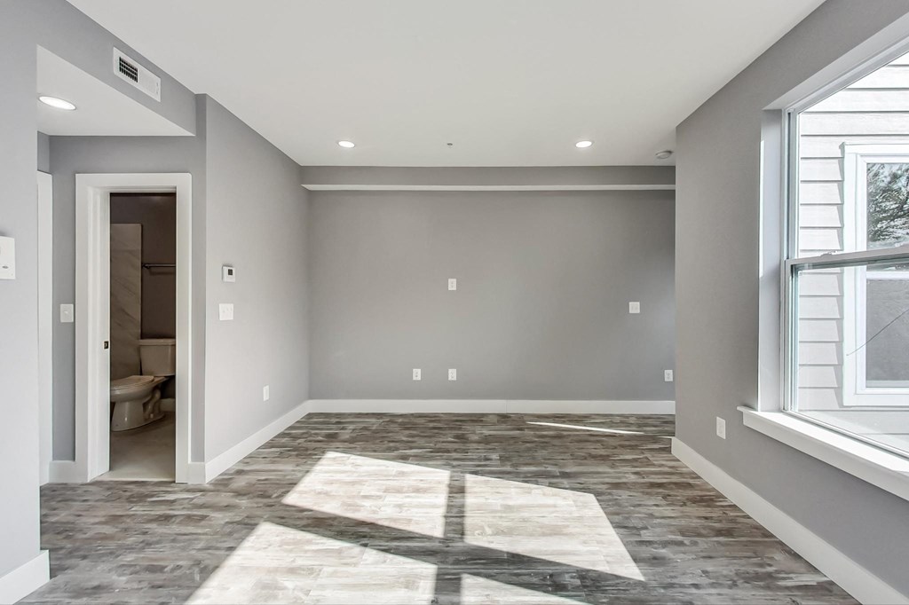 an empty room with a large window and a door to a bathroom