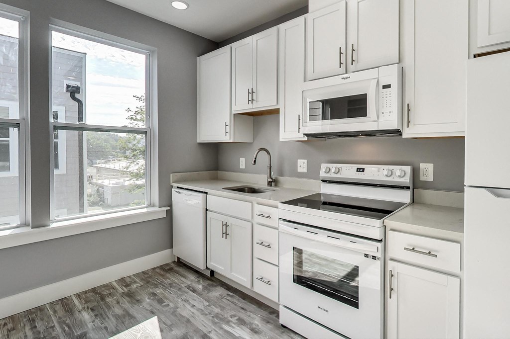 an empty kitchen with white cabinets and a window