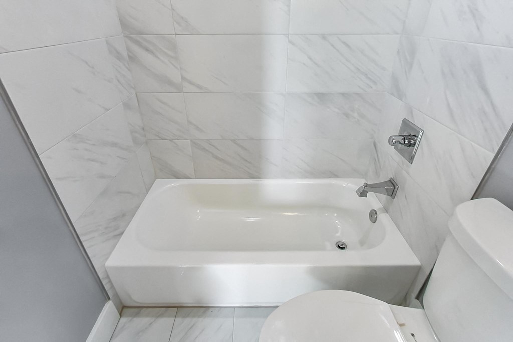 a white bathroom with a tub and a toilet