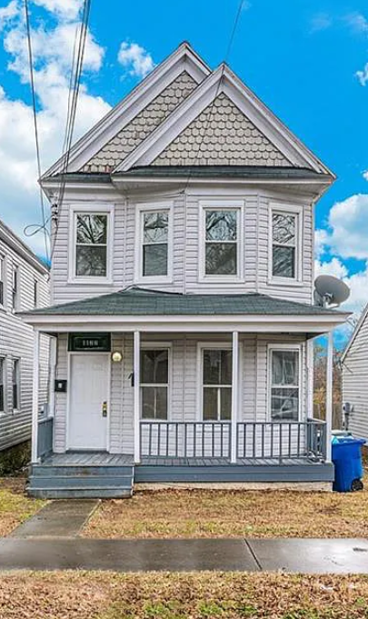 a white house with a porch and a blue sky