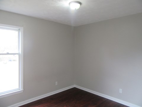 A room with a window and a wooden floor.