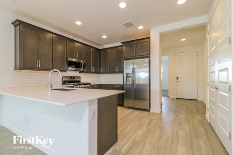a kitchen with a large island and stainless steel refrigerator