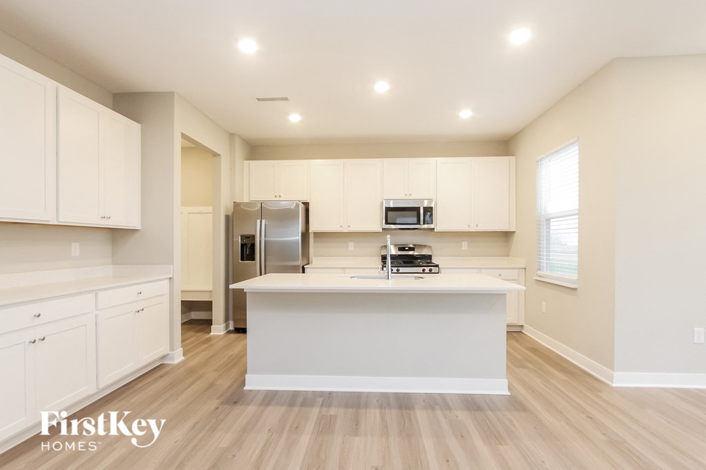 A kitchen with white cabinets and a wooden floor.