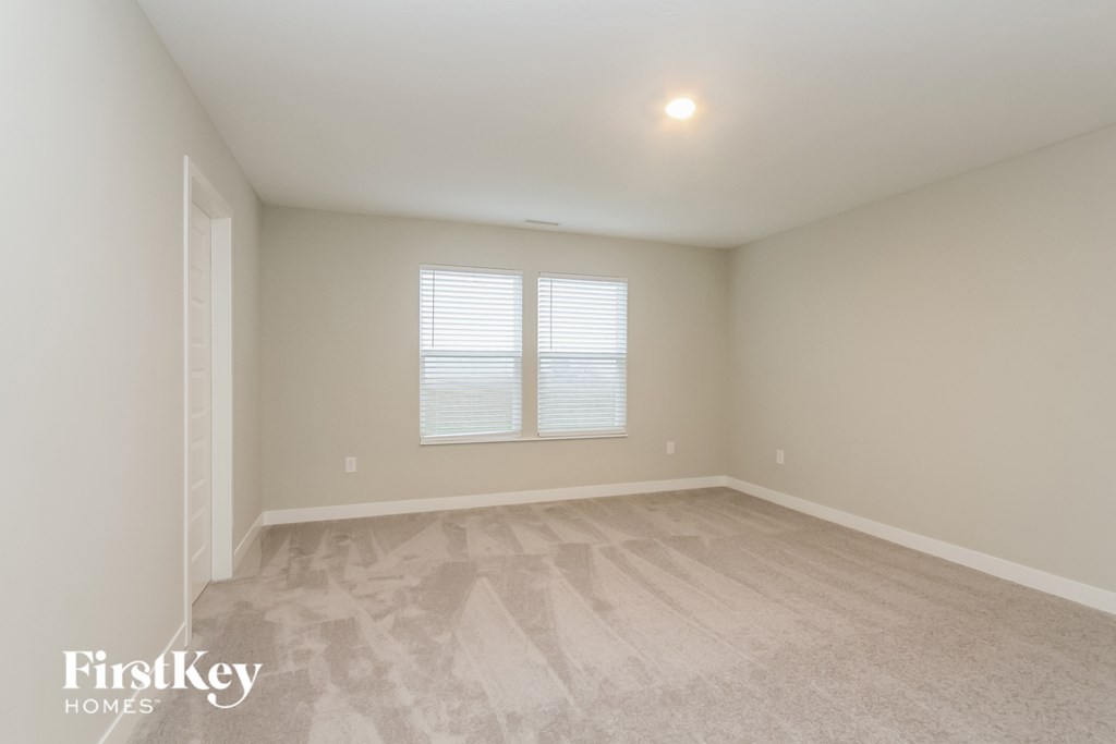 A room with a carpeted floor and a window with blinds.