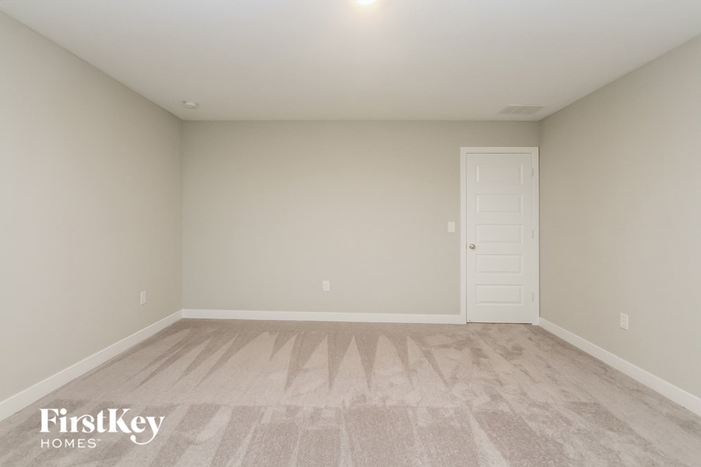 A room with a carpeted floor and a white door.