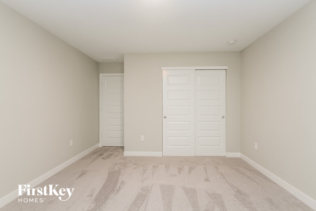A room with a carpeted floor and two white doors.