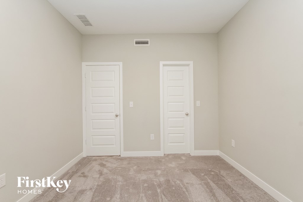 A room with two white doors and a carpet floor.