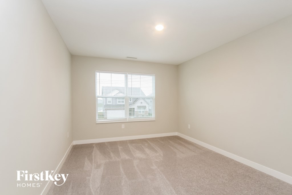 A room with a carpeted floor and a window showing a building outside.