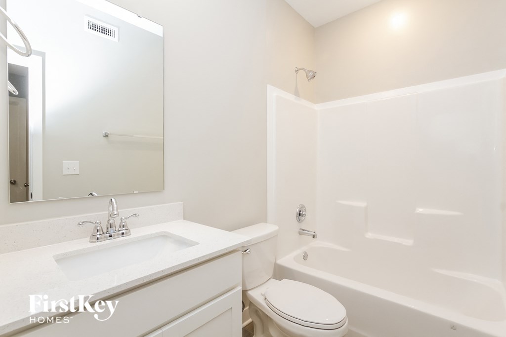 A white bathroom with a toilet, sink, and bathtub.