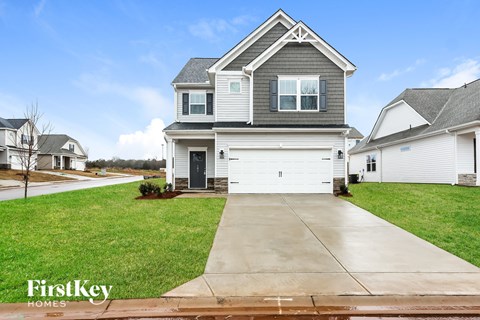 A house with a grey roof and a white garage door is for sale.