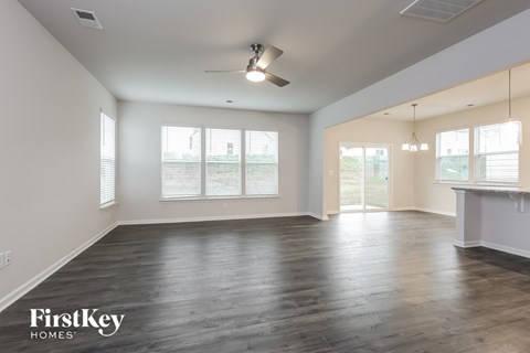 A spacious room with wooden floors and a ceiling fan.