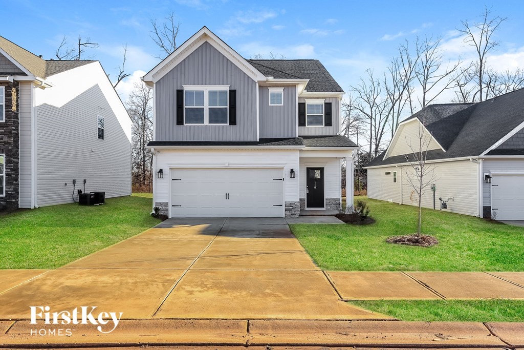 A house with a grey roof and a white garage door is for sale.