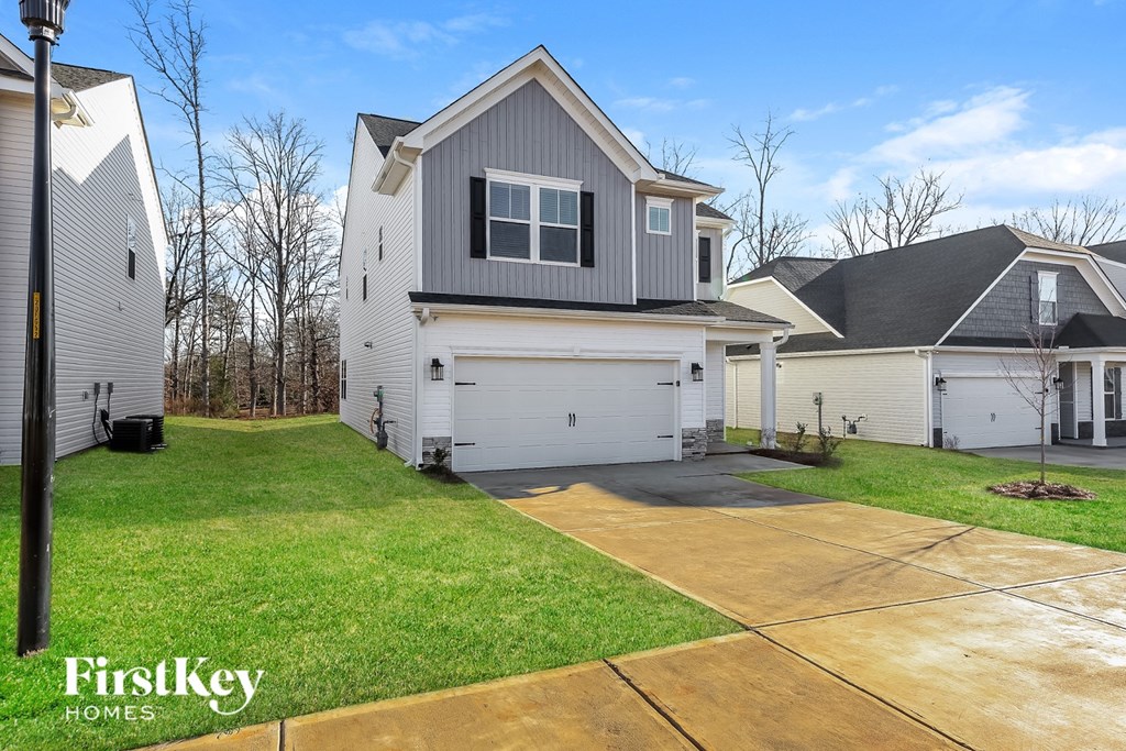 A house with a grey roof and a white garage door is for sale.