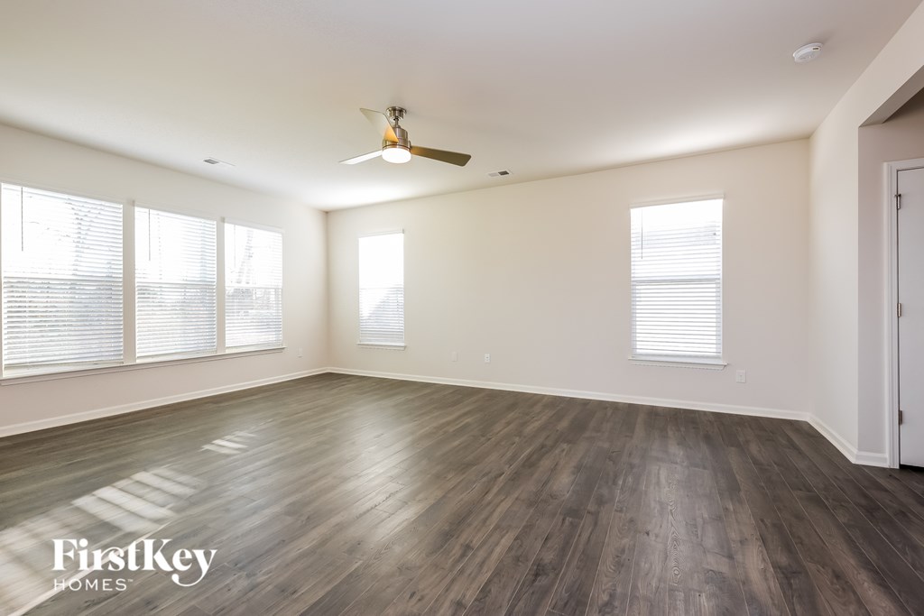 A spacious room with wooden flooring and a ceiling fan.