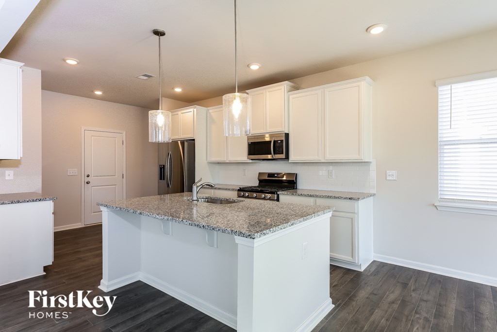 A kitchen with granite countertops and white cabinets.
