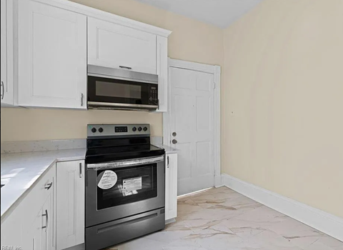 a kitchen with white cabinets and a stove and a microwave