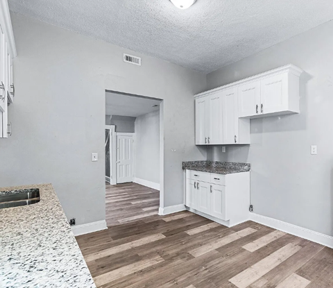 A kitchen with white cabinets and a granite countertop.