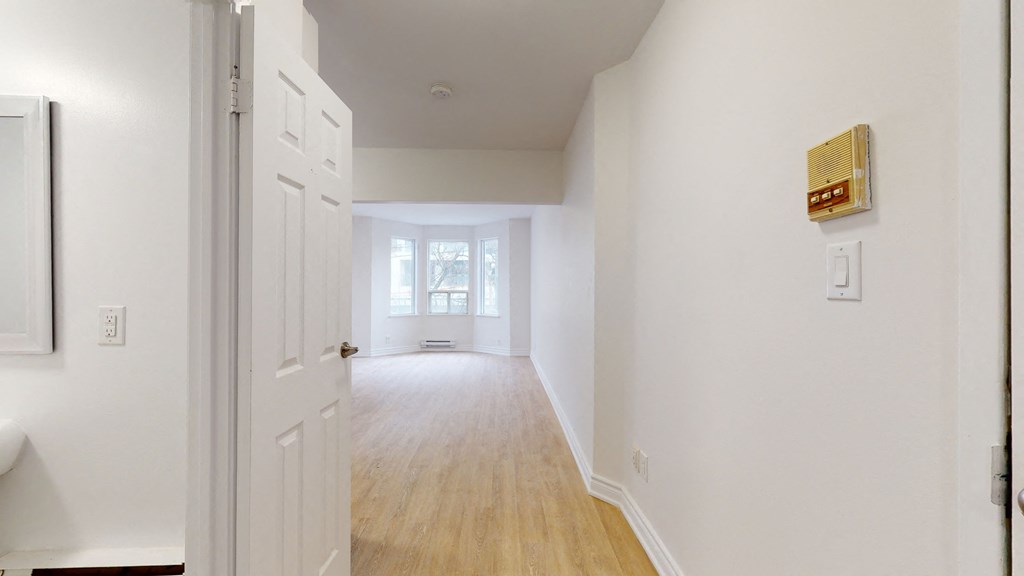 an empty room with white walls and a hallway with a white door