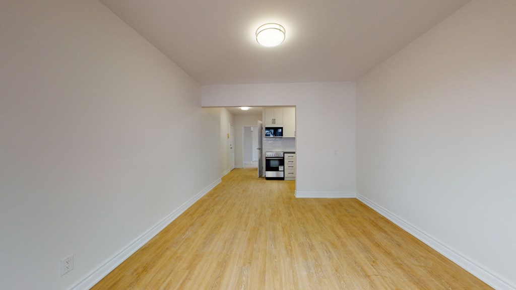 a spacious living room with white walls and wood floors