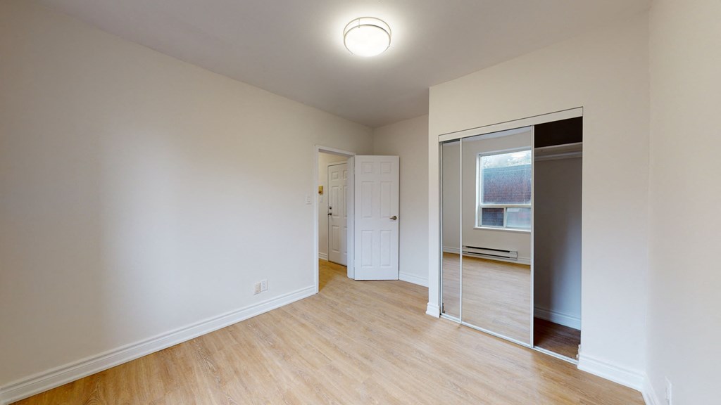 a bedroom with a mirrored closet and a door to a hallway