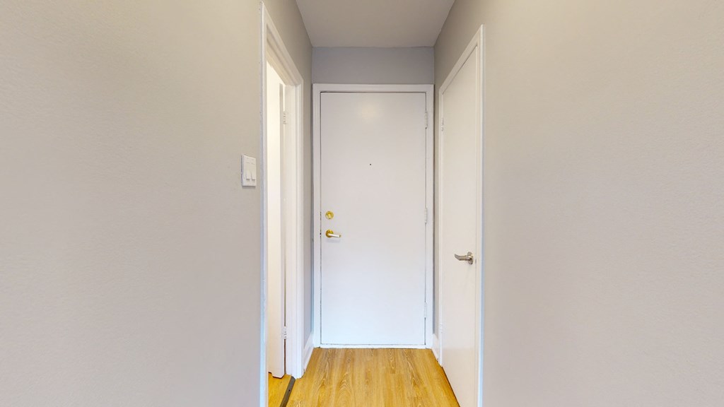 a hallway with white walls and a white door