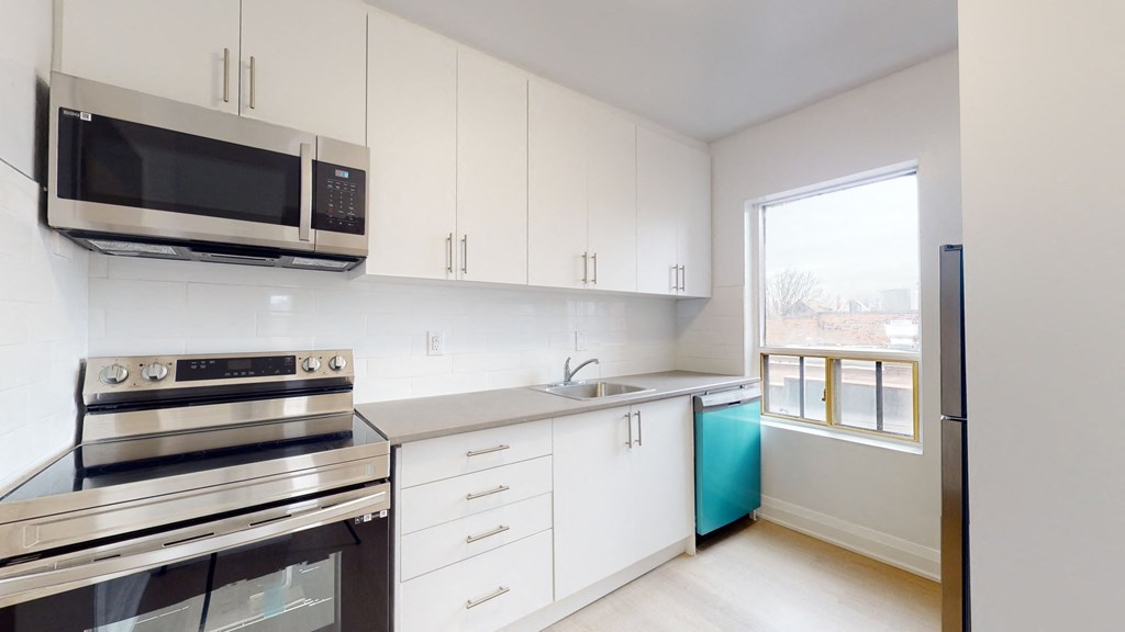 a kitchen with white cabinets and stainless steel appliances and a window