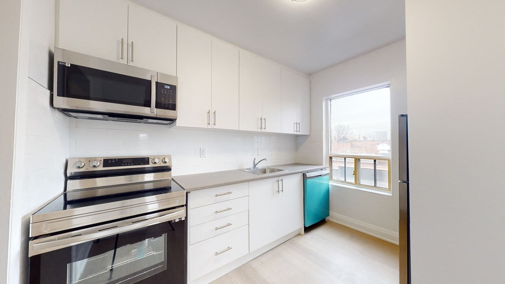 a kitchen with white cabinets and stainless steel appliances and a window