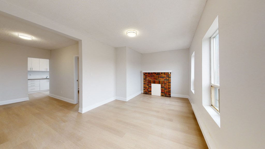 the living room and dining room of an empty house with white walls and a fireplace