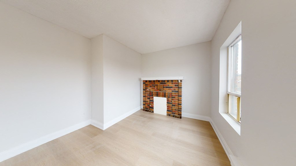 an empty room with a fireplace and wooden floors