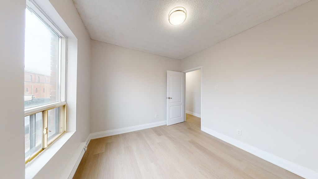 a spacious living room with a large window and wood flooring