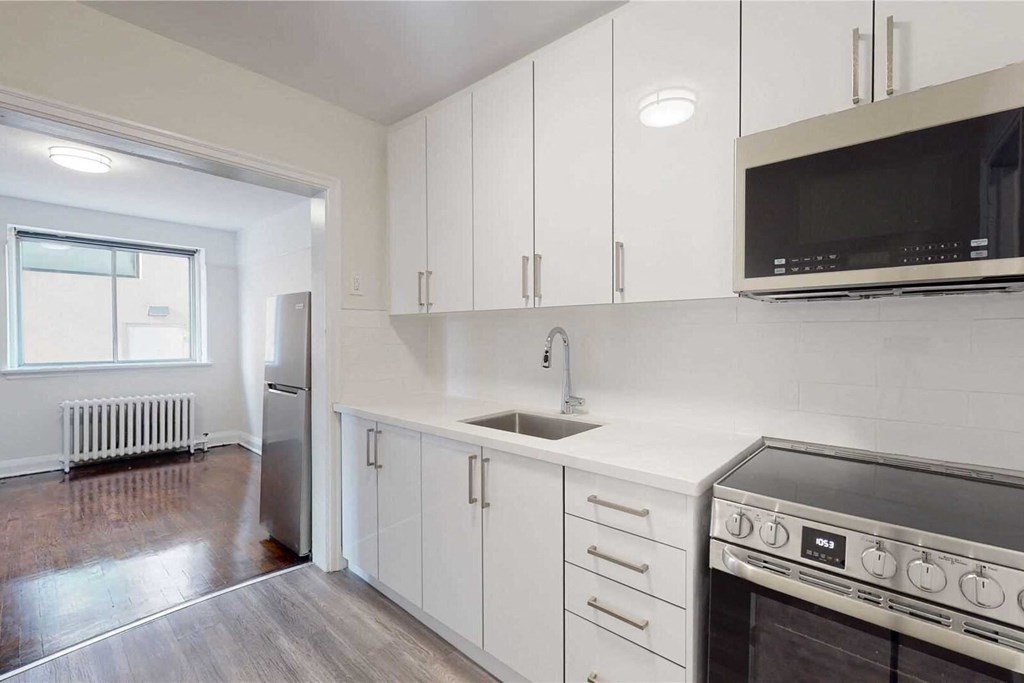 an empty kitchen with white cabinets and a sink