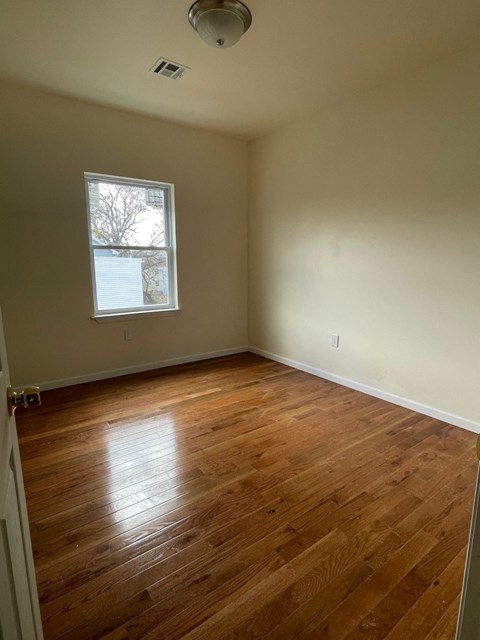an empty room with wooden floors and a window