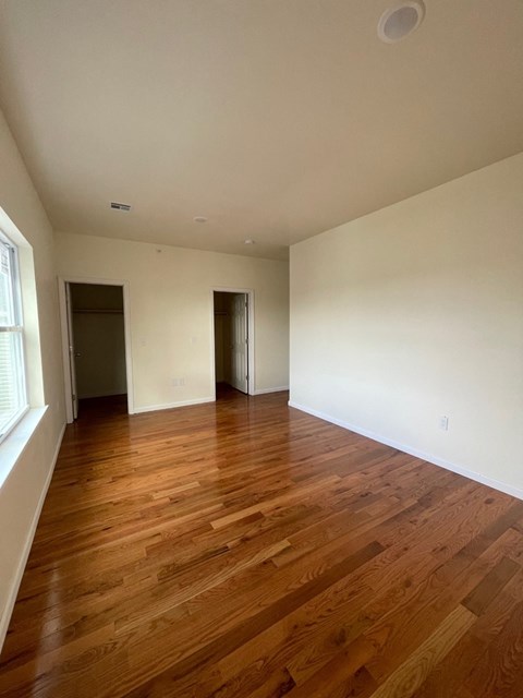 an empty living room with wood flooring and white walls