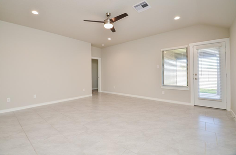 A spacious room with a ceiling fan and a door leading to another room.