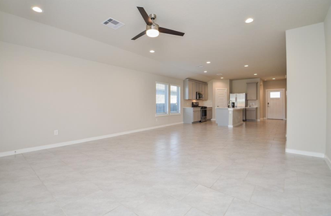 A spacious living room with a ceiling fan and tiled flooring.