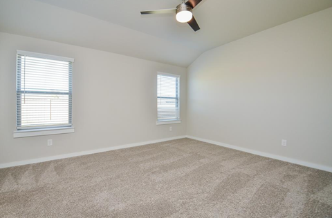 A room with a ceiling fan and two windows.