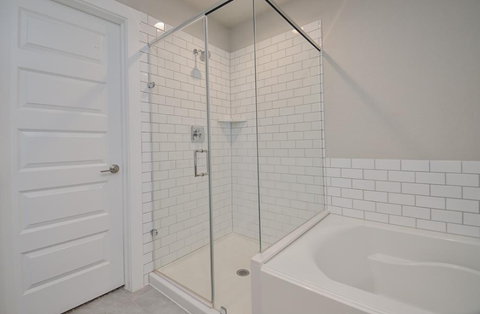 A white bathroom with a white tub and a white door.