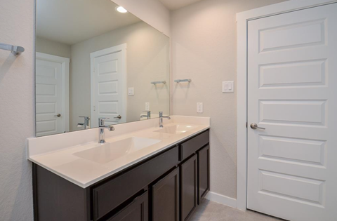 A bathroom with a white sink and brown cabinets.