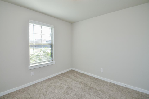 A room with a window and carpeted floor.