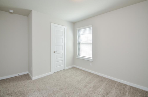 A room with a door and a window with blinds.
