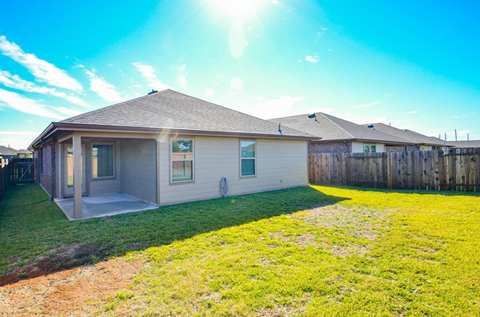 A house with a brown roof and a green lawn in front.