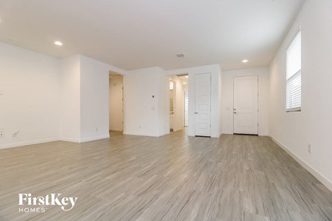 A spacious empty room with wooden flooring and white walls.