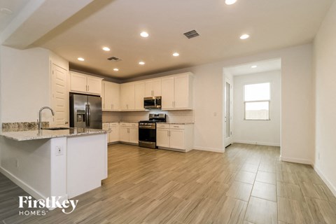 A kitchen with white cabinets and a wooden floor.