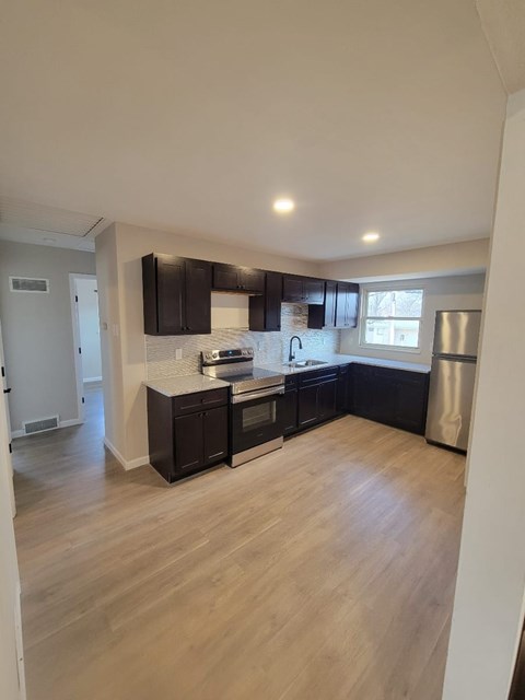 A kitchen with dark wood cabinets and a stainless steel refrigerator.
