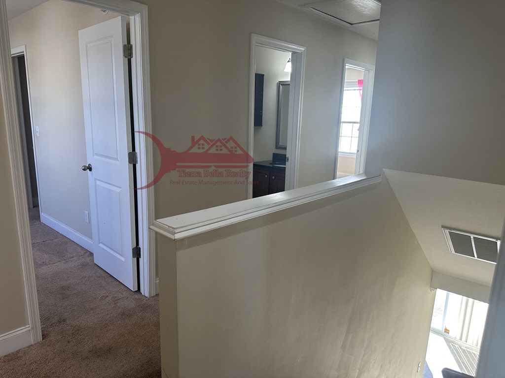 a view from the top of the stairs looking into the hallway and into the bedroom