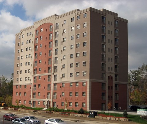 A large red and beige building with a parking lot in front.