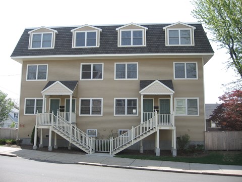 a yellow house with a front porch and stairs